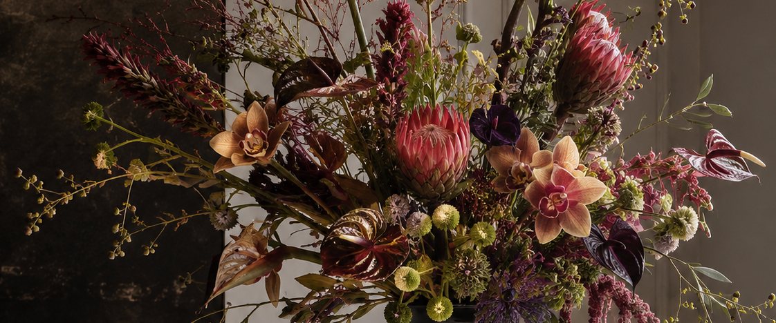Stillleben aus schwarzer Keramikvase und wildem Blumenflor
